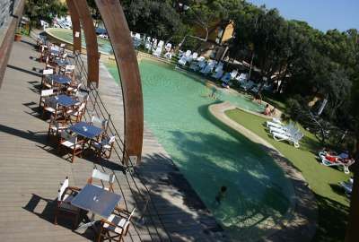 Piscina all'aperto con sedie e tavoli su un pontile.