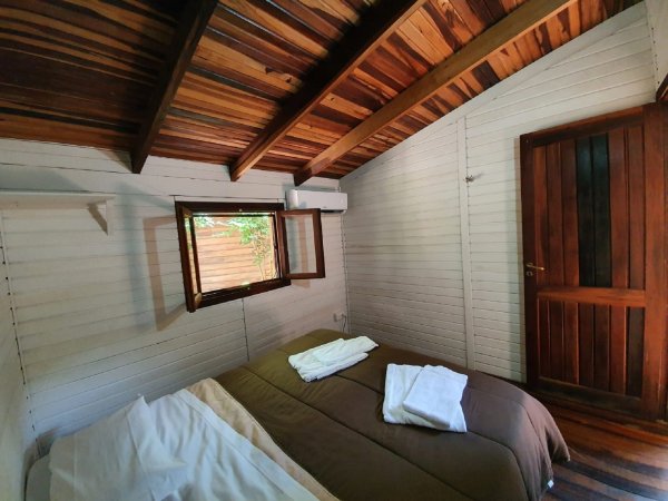 Camera da letto con letto matrimoniale e finestra, pareti in legno.