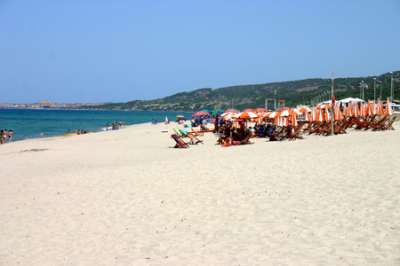 Spiaggia sabbiosa con sdraio e ombrelloni arancioni.