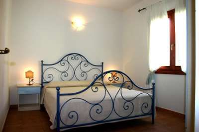 Stanza con letto in ferro battuto e due lampade.