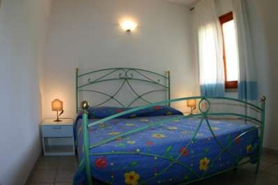 Camera con letto matrimoniale, copriletto blu a fiori, lampade sui comodini.