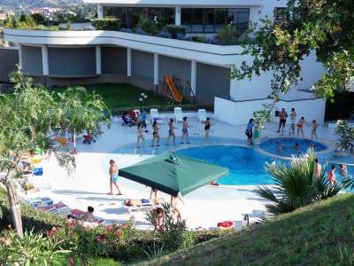 Persone attorno a una piscina all'aperto di un complesso moderno.