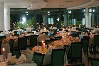 Un ristorante elegante con tavoli apparecchiati e candele accese.