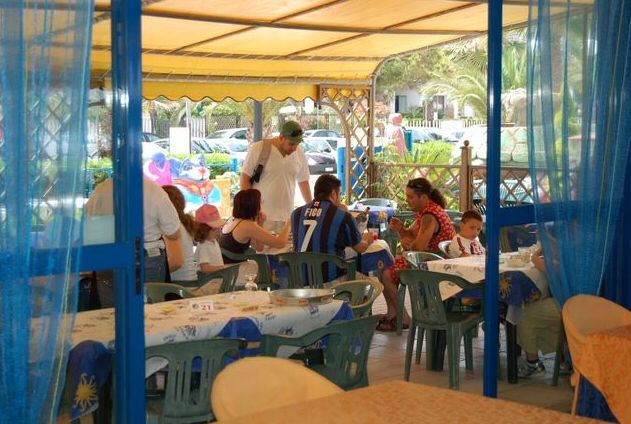 Famiglia seduta a tavoli all'aperto di un ristorante.