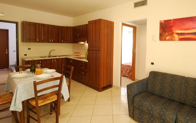 Cucina abitabile con mobili in legno, tavolo da pranzo apparecchiato e divano blu.