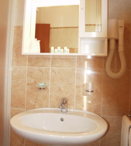 Lavabo da bagno con specchio, asciugacapelli e dispenser.