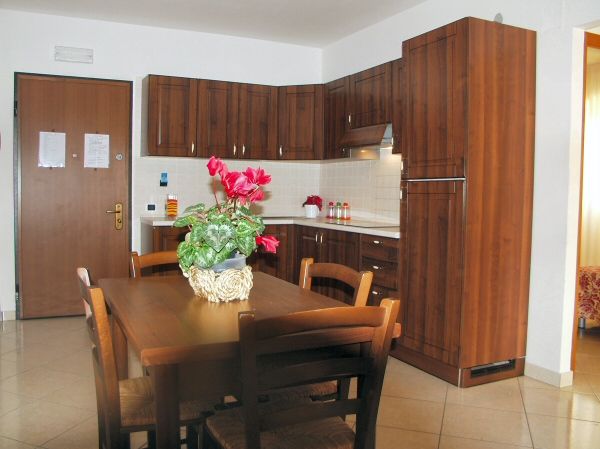 Cucina moderna con mobili in legno scuro e un tavolo da pranzo con fiori su di esso.
