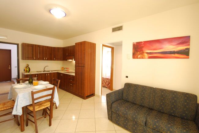 Cucina in legno con tavolo apparecchiato e divano, decorata con un dipinto colorato.