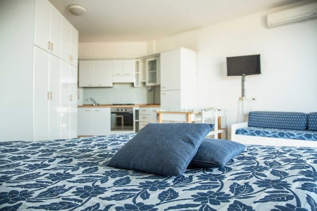 Camera con letto, cucina e TV a muro.