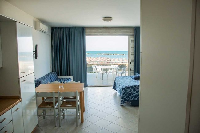 Stanza con tavolo, letto e vista mare.