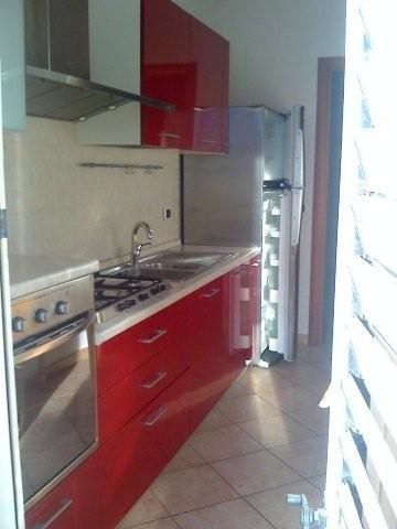 Cucina moderna con mobili rossi, piano cottura e frigorifero.