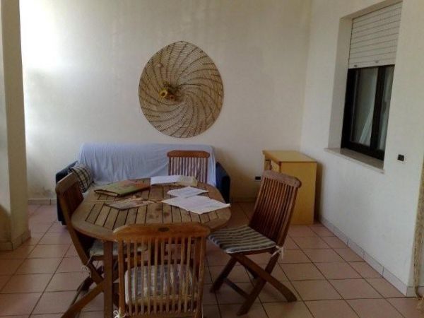 Soggiorno con tavolo rotondo in legno, sedie e divano blu.