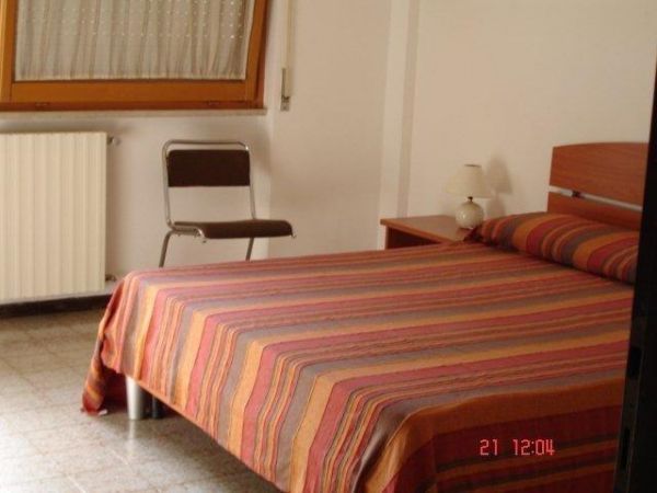 Camera da letto con letto a righe colorate e finestra.