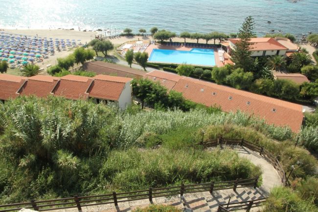 Vista su una spiaggia, piscina e tetti rossi.