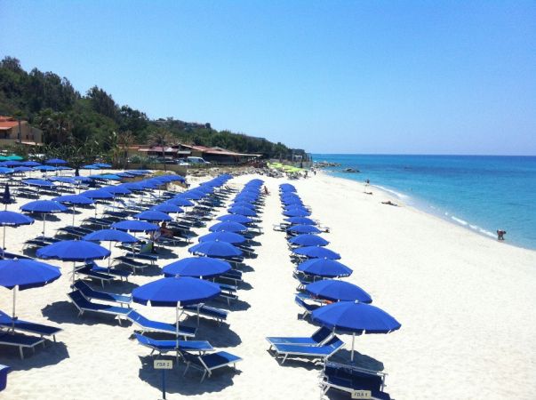 Ombrelloni blu su una spiaggia soleggiata.