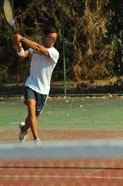Uomo gioca a tennis su un campo all'aperto.