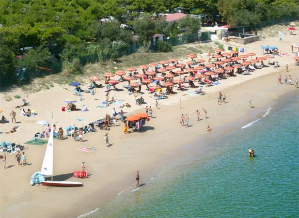 Spiaggia affollata con ombrelloni arancioni.