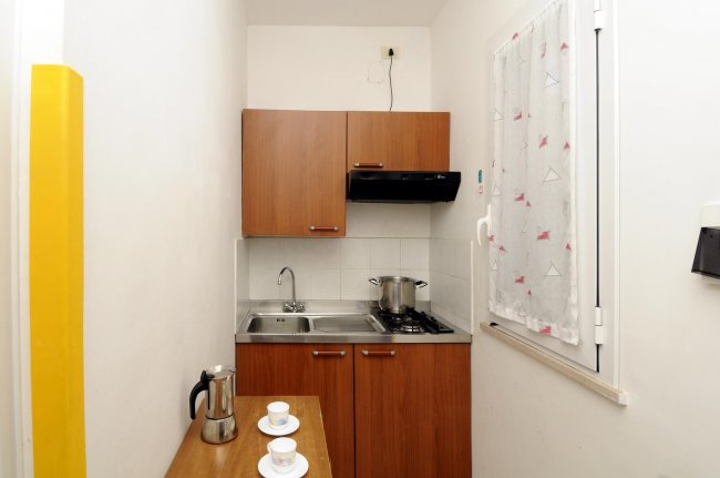 Cucina compatta con tazze e caffettiera.