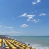 Spiaggia con ombrelloni gialli allineati sotto un cielo azzurro.