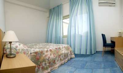 Una camera con letto matrimoniale, tende azzurre e pavimento blu.