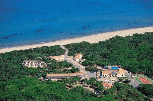 Veduta aerea di un complesso vicino a una spiaggia con acqua blu e una zona verde attorno.