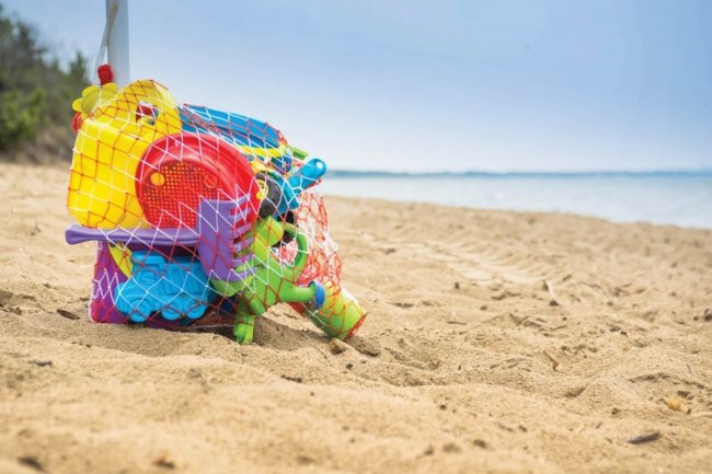 Una rete contenente giochi colorati sulla sabbia con il mare sullo sfondo.