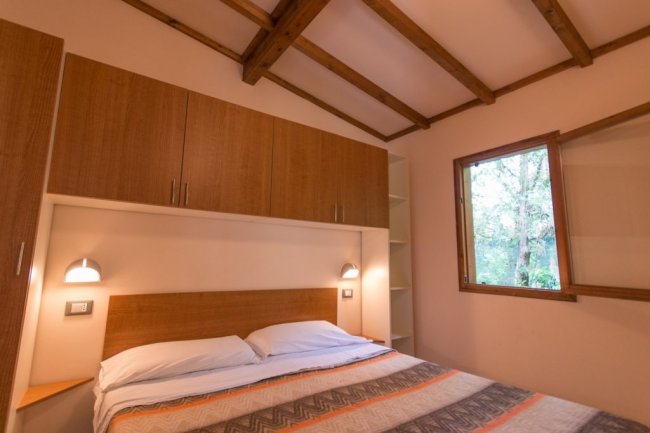 Camera con un letto matrimoniale, armadi di legno e una finestra.