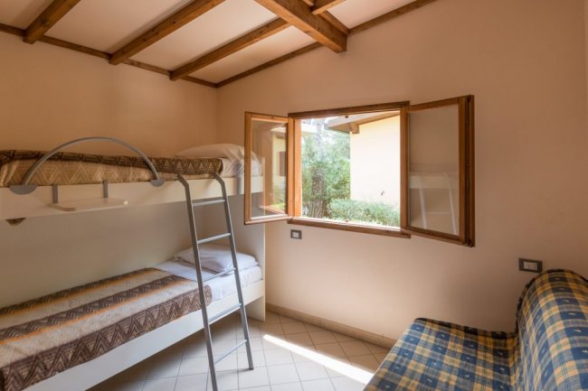 Cameretta con letto a castello, finestra aperta e divano blu a quadri.