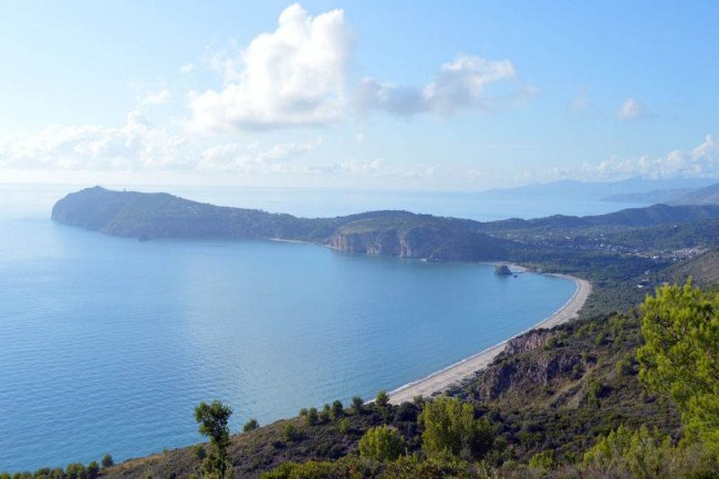 Spiaggia e costa montuosa con cielo blu.