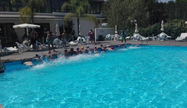 Persone in fila lungo una piscina.