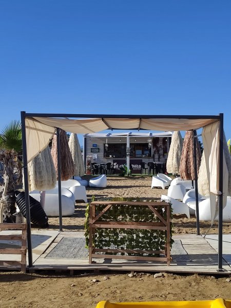 Area esterna con sedie bianche e ombrelloni.