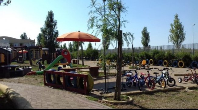 Parco giochi con biciclette e ombrelloni.