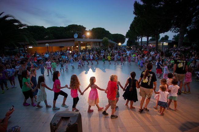Gruppo di bambini che ballano in cerchio al tramonto.