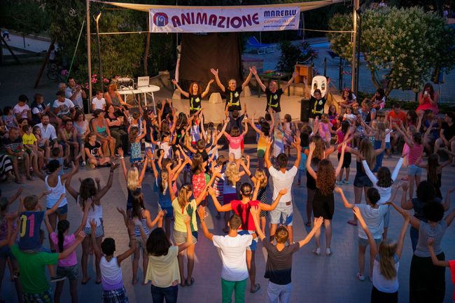 Bambini e animatori ballano insieme.