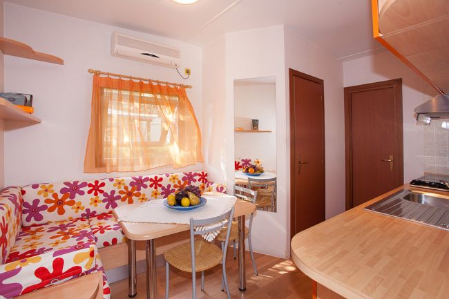 Cucina e salotto colorati con divano floreale e tavolo, ben illuminata.