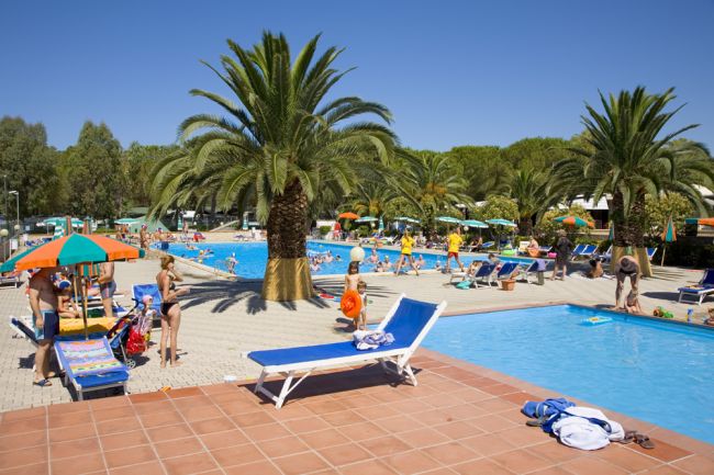 Piscina all'aperto con persone e palme.