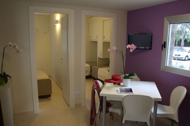 Interno di una stanza con tavolo, sedie e parete viola.