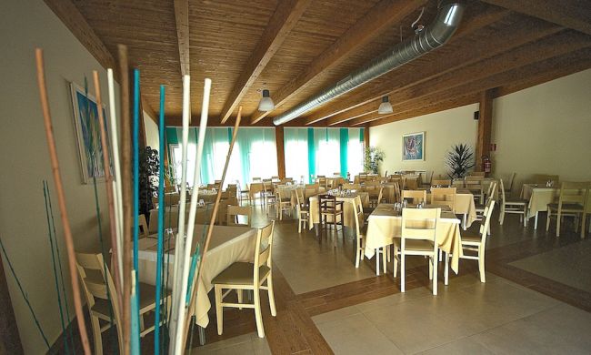 Sala da pranzo con tavoli apparecchiati e soffitto in legno.