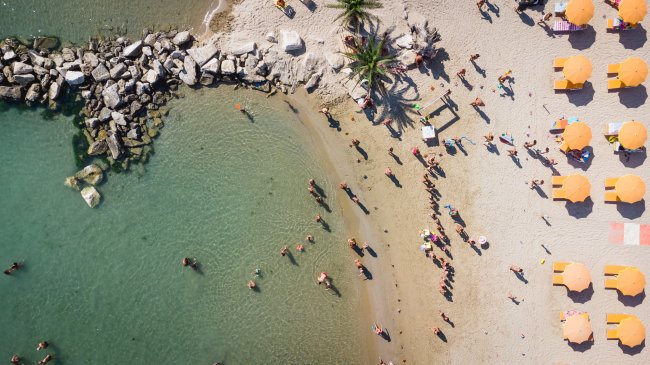 Spiaggia con ombrelloni arancioni e persone in acqua.