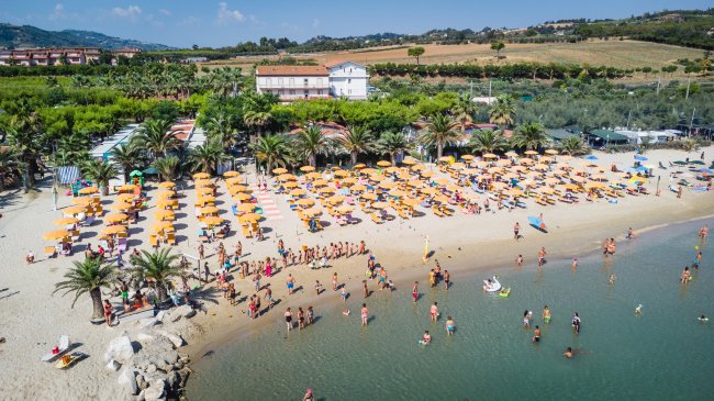 Veduta aerea di una spiaggia affollata con ombrelloni gialli.