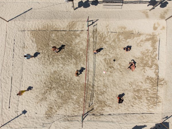 Partita di beach volley vista dall'alto su sabbia.