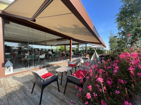 Terrazza esterna con sedie e fiori rosa.