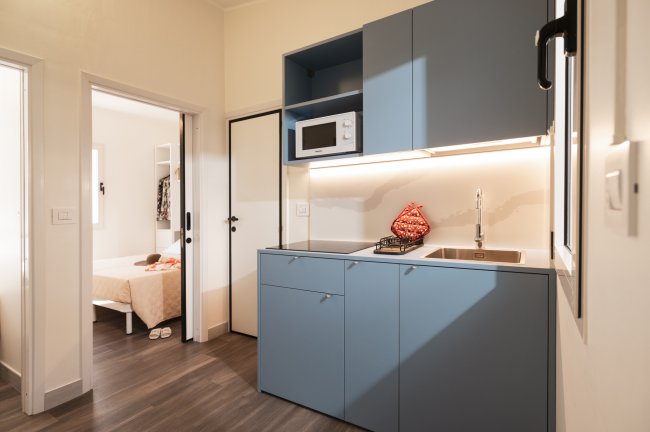 Cucina moderna con mobili blu e microonde.