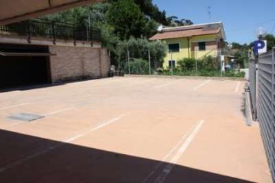 Un parcheggio vuoto con un edificio giallo sullo sfondo.