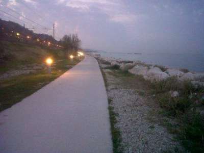 Un sentiero costiero con luci e mare al tramonto.