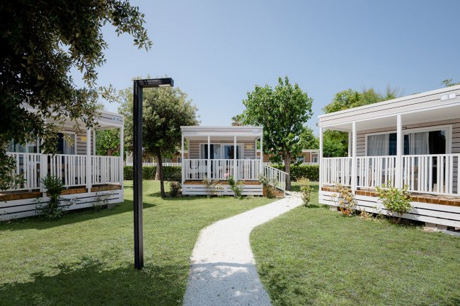 Giardino con case mobili, sentiero centrale.
