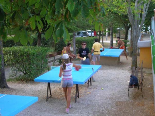 Persone che giocano a ping pong su tavoli all'aperto.