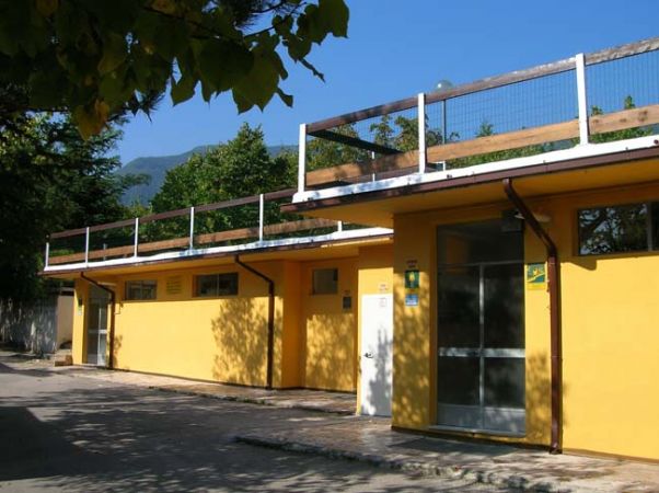 Edificio giallo con terrazza e cancellata in un giorno soleggiato.
