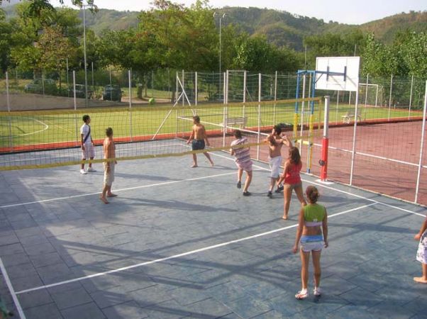 Persone giocano a pallavolo su un campo all'aperto.