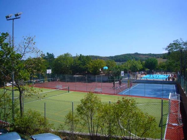 Vista di un campo sportivo all'aperto con recinzione, accanto a una piscina.